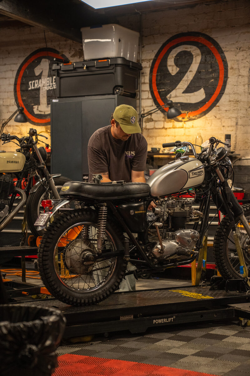Workshop member working on a motorcycle with professional tools