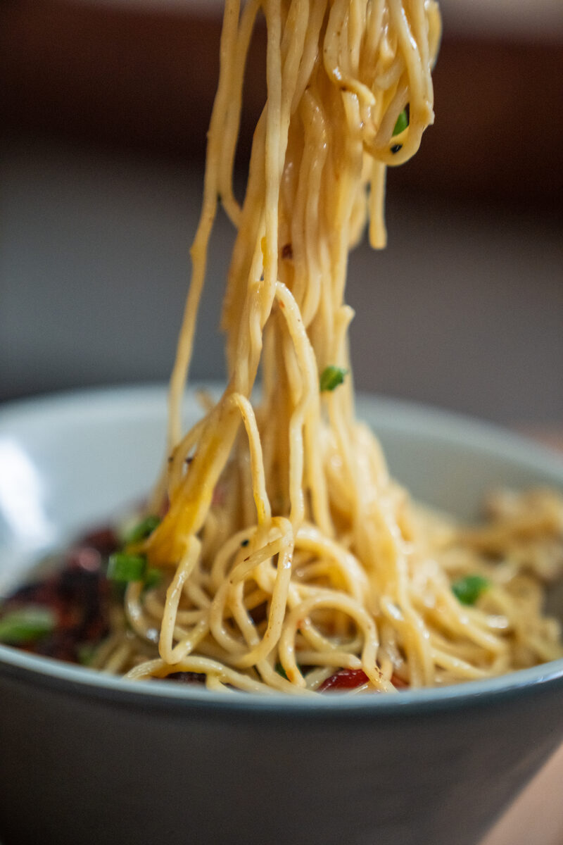 Noodle pull from a steaming bowl of ramen